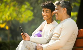 Father and son looking at their phone and smiling