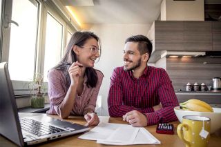 A young smiling couple at a kitchen table