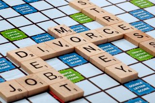 A game board with letter tiles spelling "divorce, debt, money and stress"