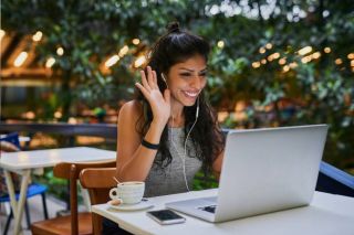 Woman waving and smiling at the laptop