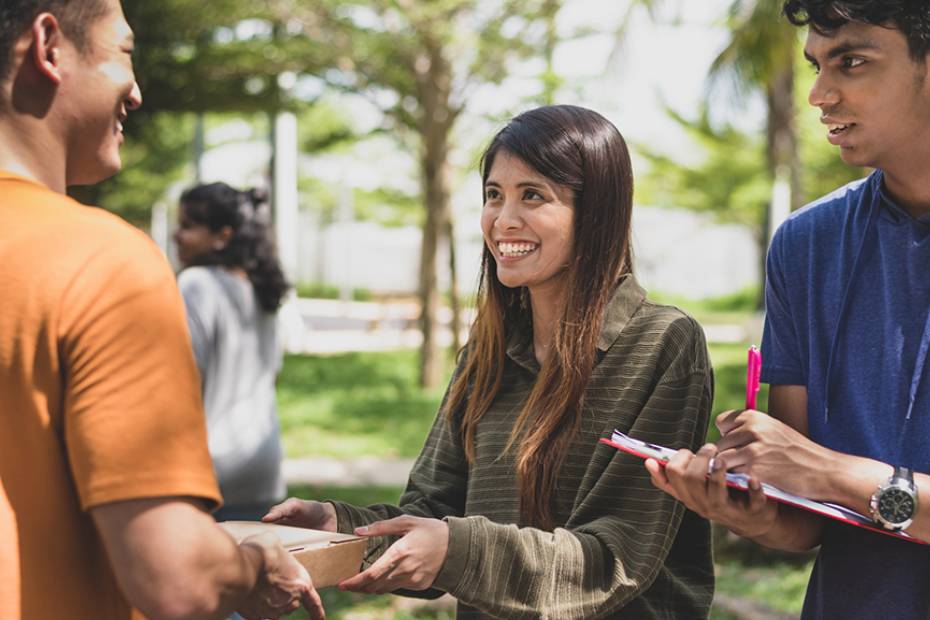 Two volunteers accept a donation in a park.