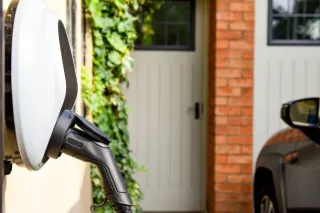 Close up of hand inserting plug into electric vehicle.