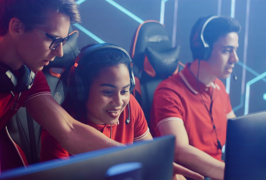 A smiling female student with two male students in a high-tech computer lab learning cyber security skills as part of CanHack 2022