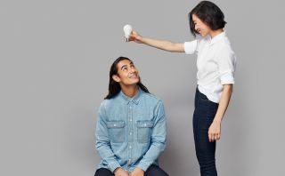 A lady holding a lightbulb above a mans head