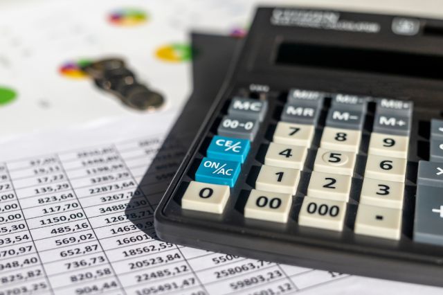 A desk covered in spreadsheets and a calculator