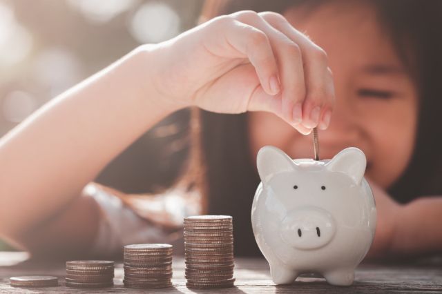 Young girl with a piggy bank and cash in hand, dreaming about the future