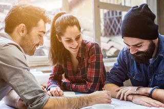 Three university students studying at a table outdoors