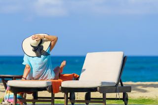 Beautiful female in sun hat resting by the edge of a swimming pool during her snowbird vacation.