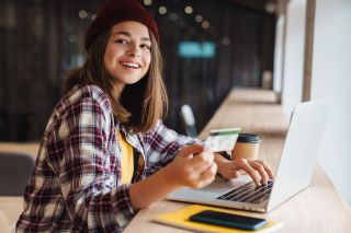 Young female student on laptop with a credit card