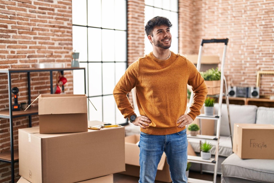 Smiling young male newcomer standing in a newly rented home