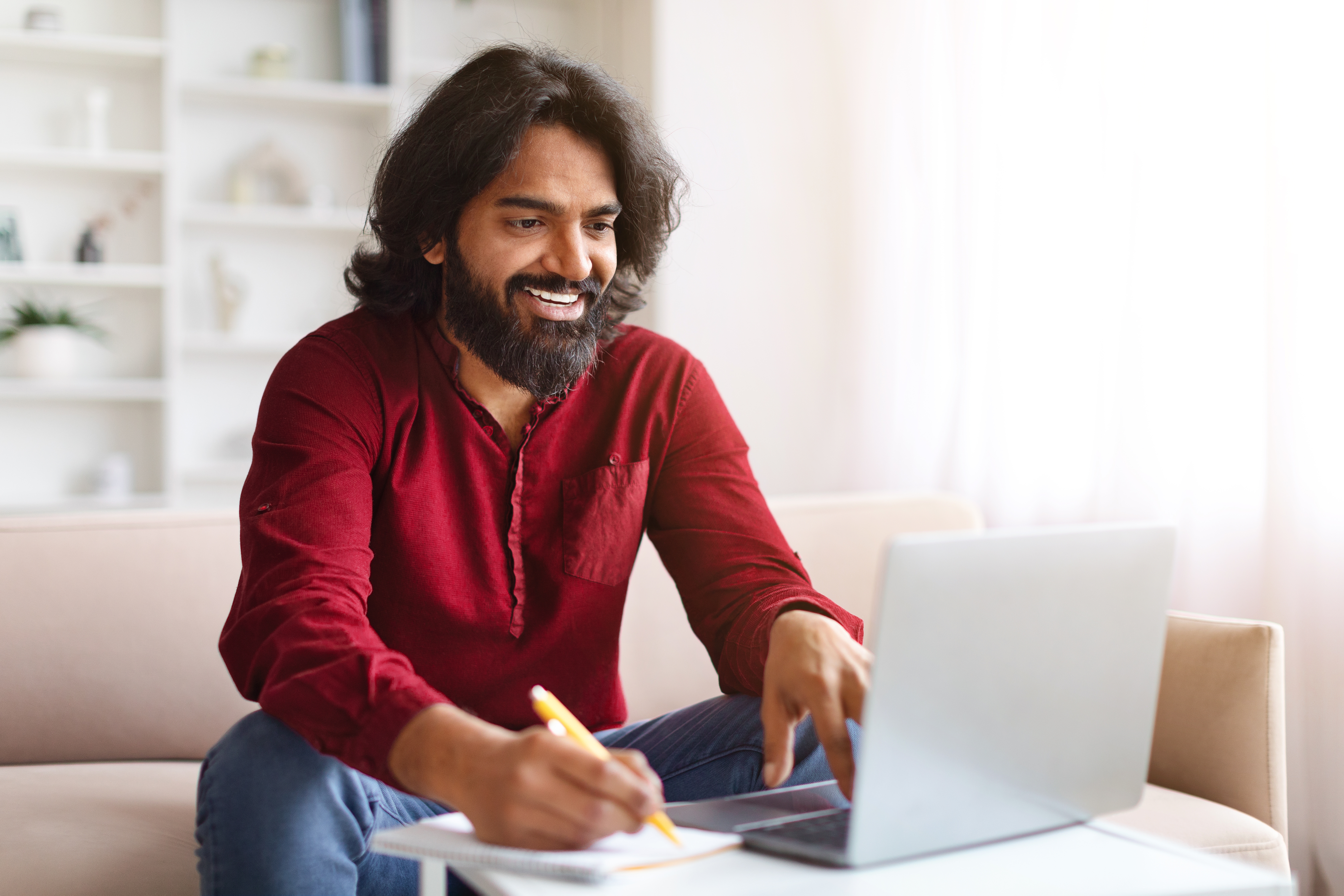 Man sitting and completing online training on a laptop at home.