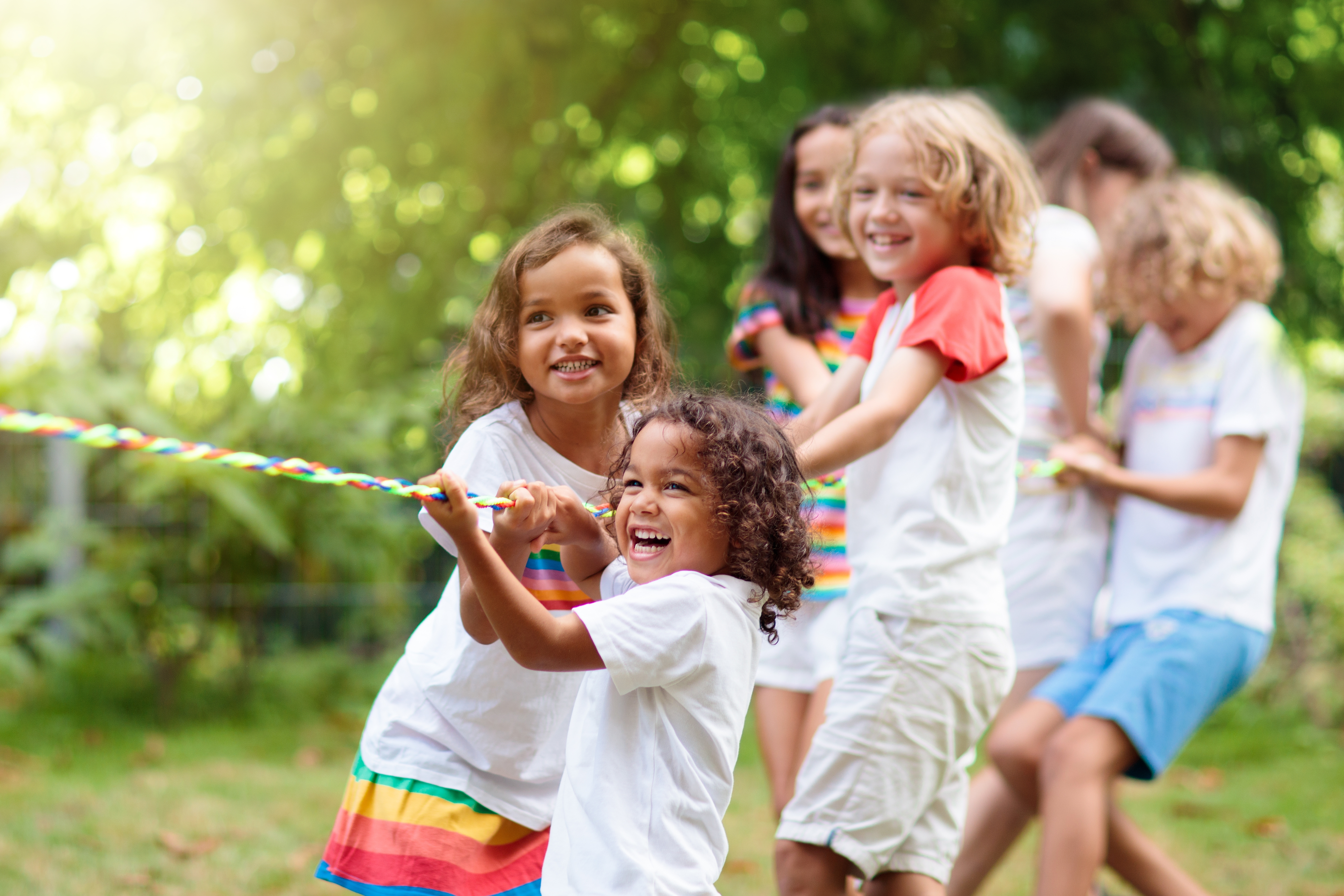 Kids play tug of war in a sunny park