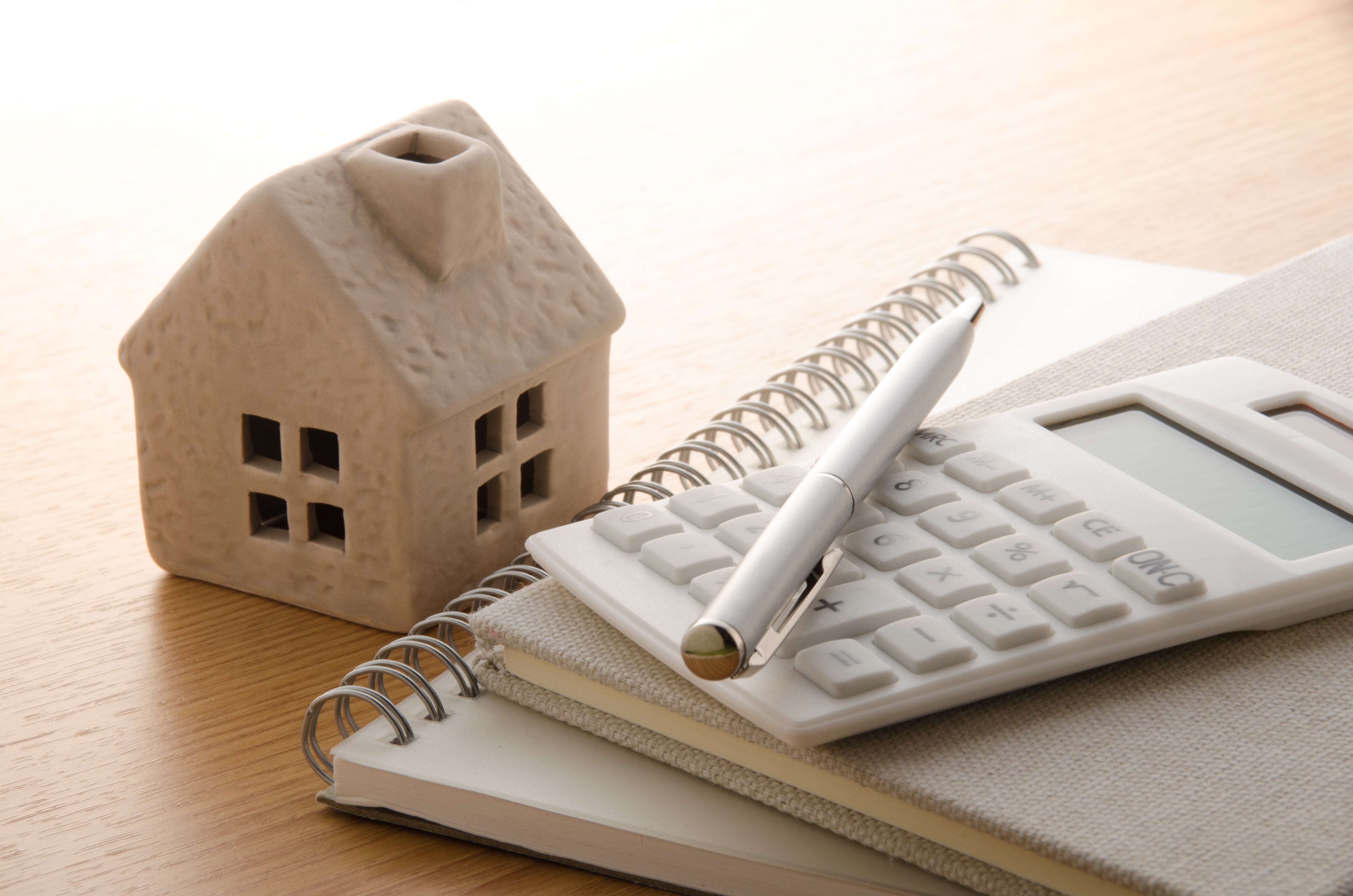 A wooden toy house next to a notepad