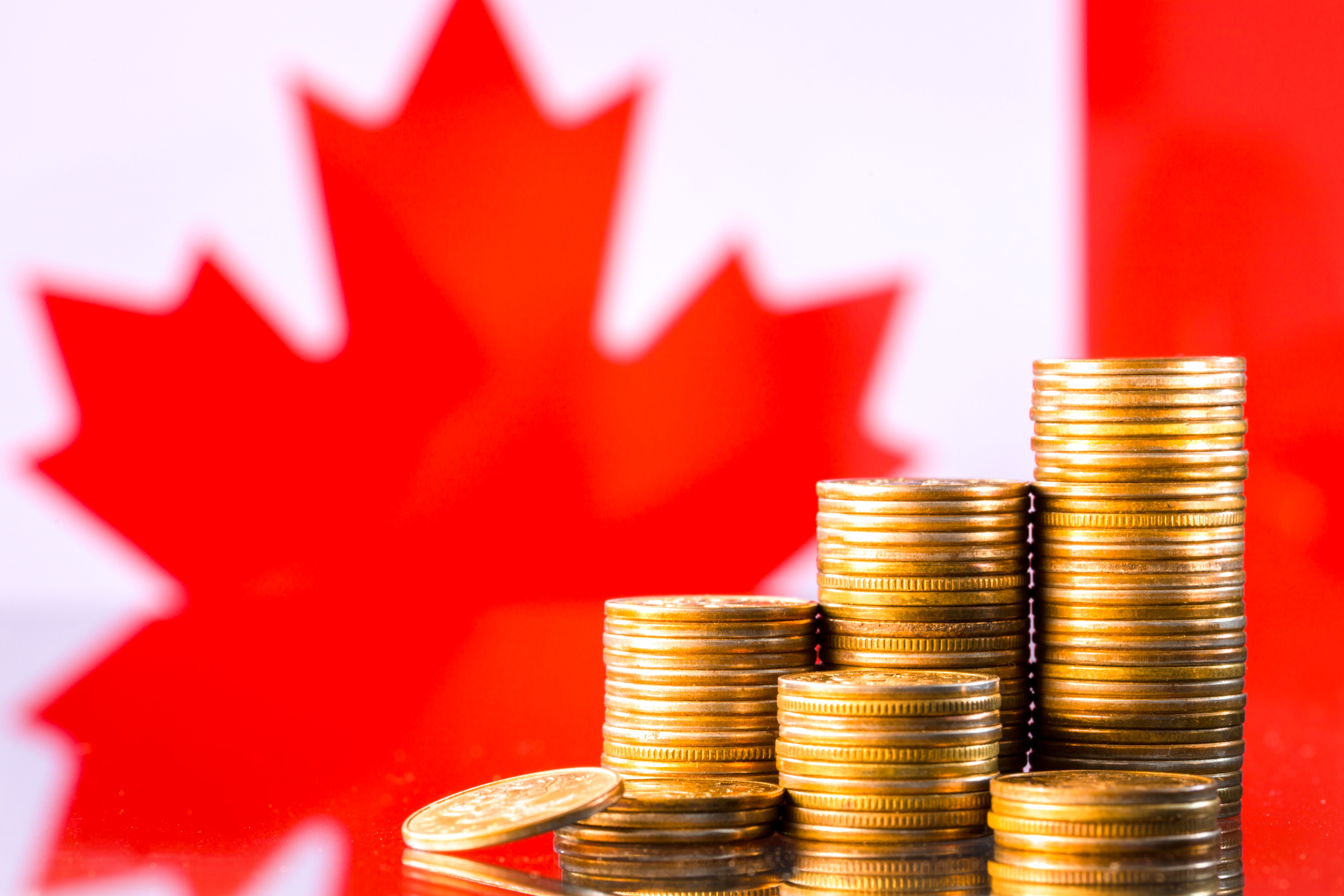 A stack of gold coins in front of a Canadian flag