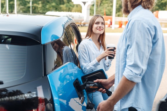 A woman leaning against a car