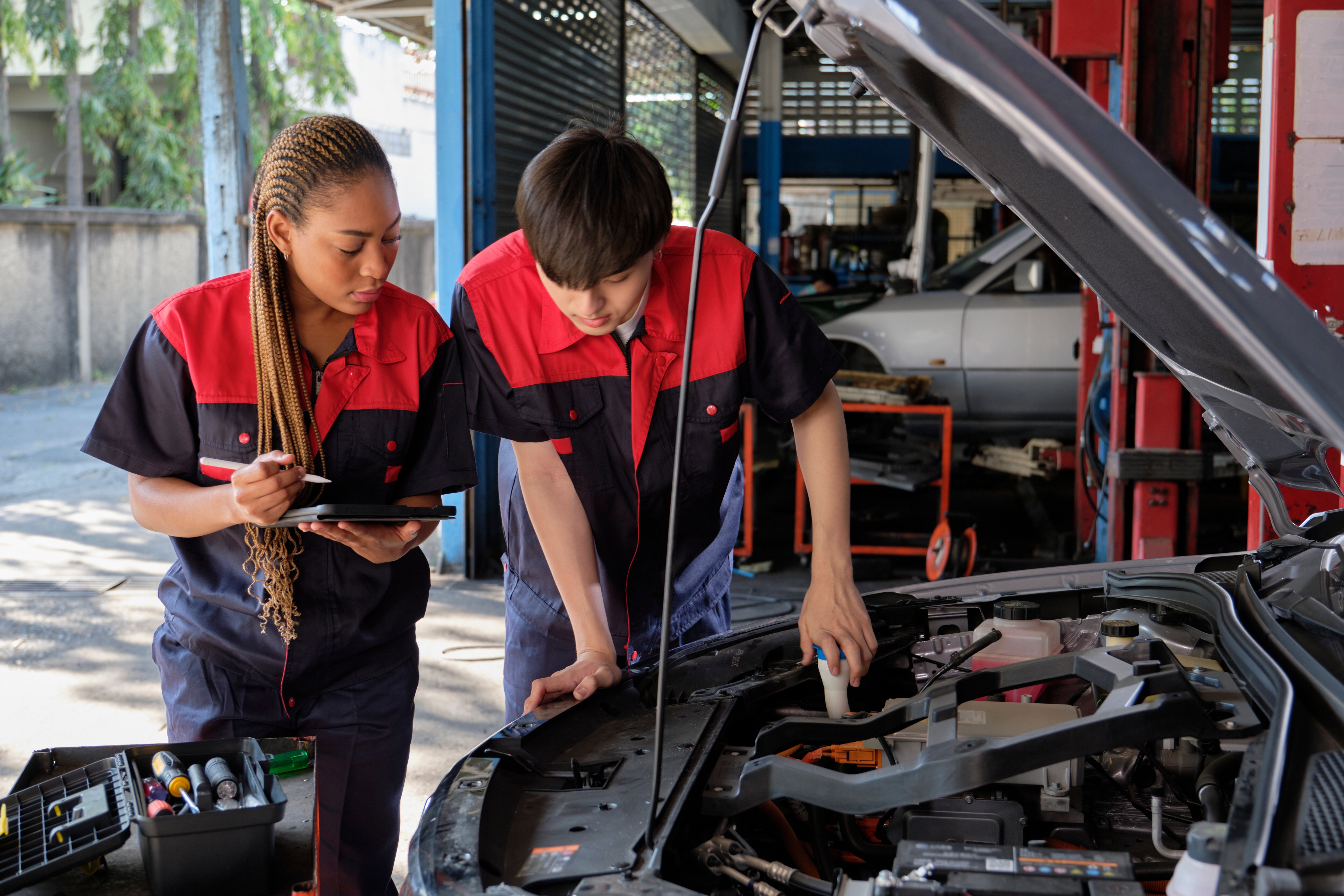 Two mechanics checking and repairing a car