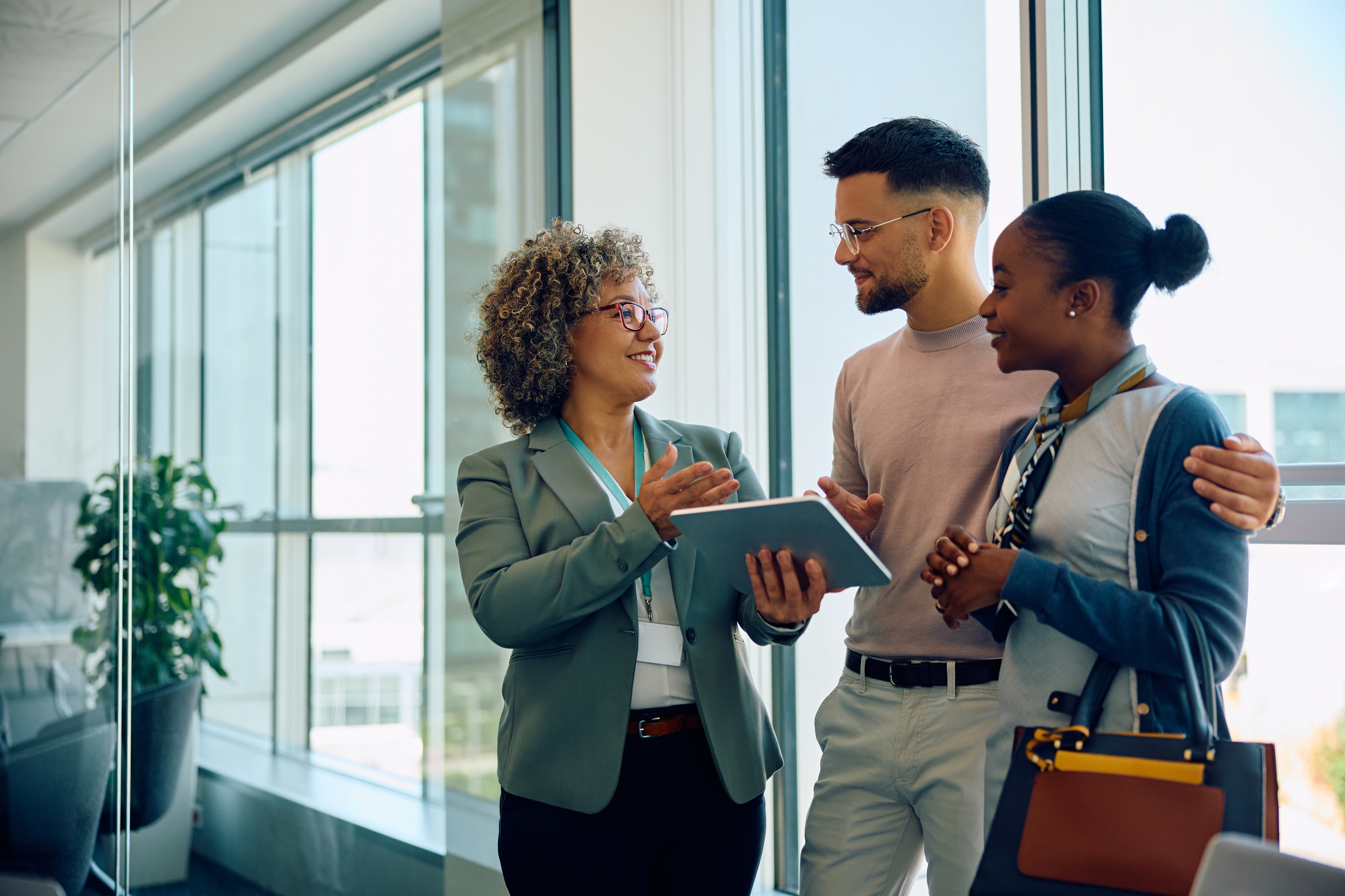 A financial advisor pleasantly explaining financial plans to a newcomer couple in Canada. The article highlights the importance of seeking the assistance of a financial advisor for newcomers.