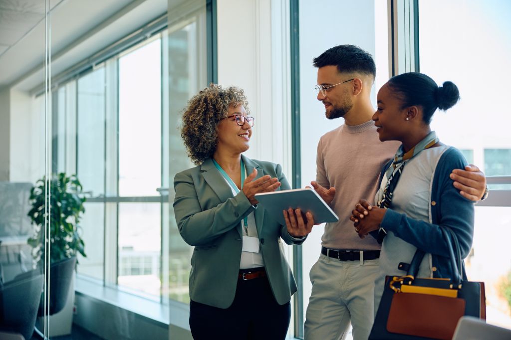 A financial advisor pleasantly explaining financial plans to a newcomer couple in Canada. The article highlights the importance of seeking the assistance of a financial advisor for newcomers.