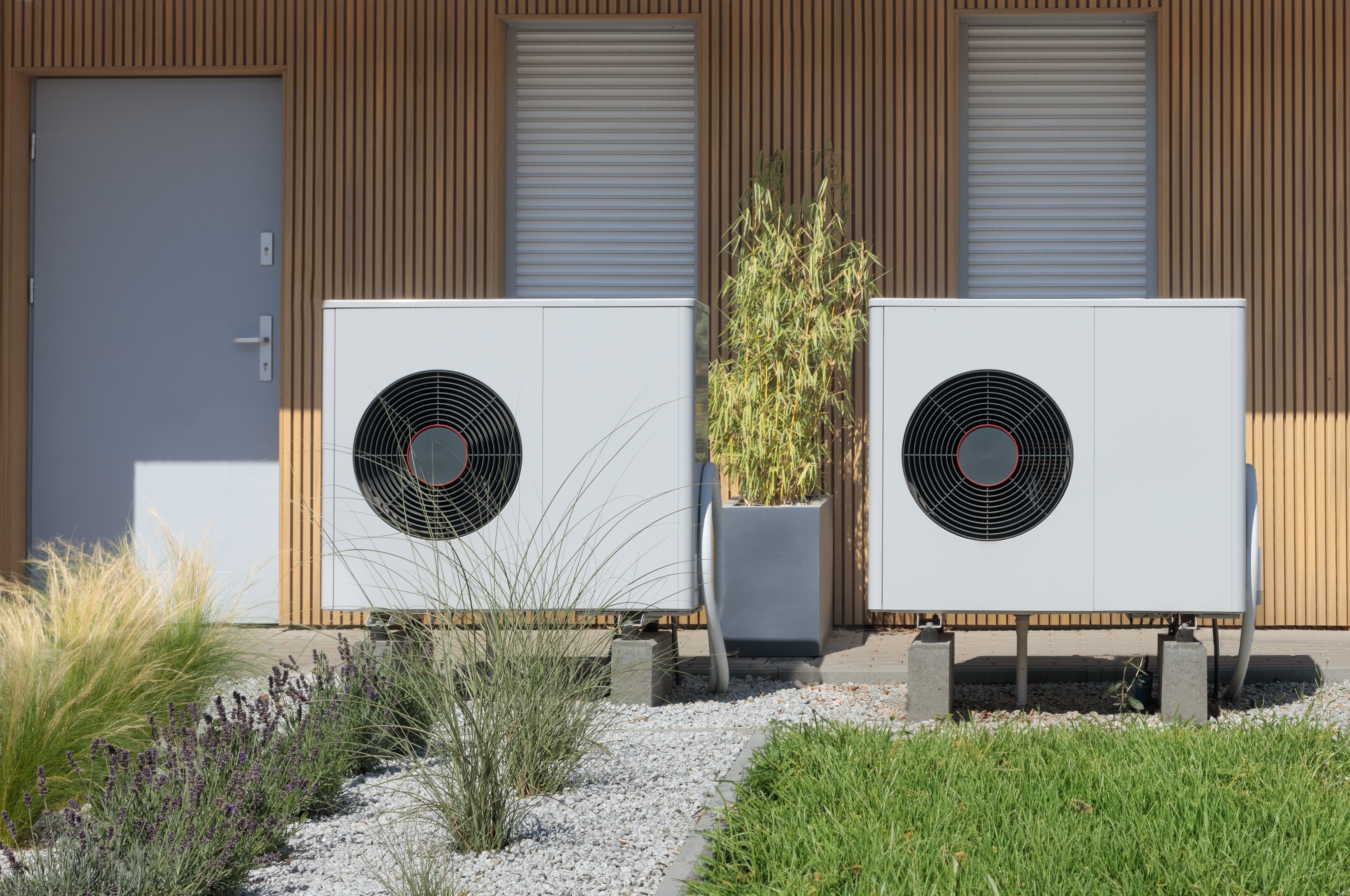 Two air-source heat pumps outside a modern energy-efficient home