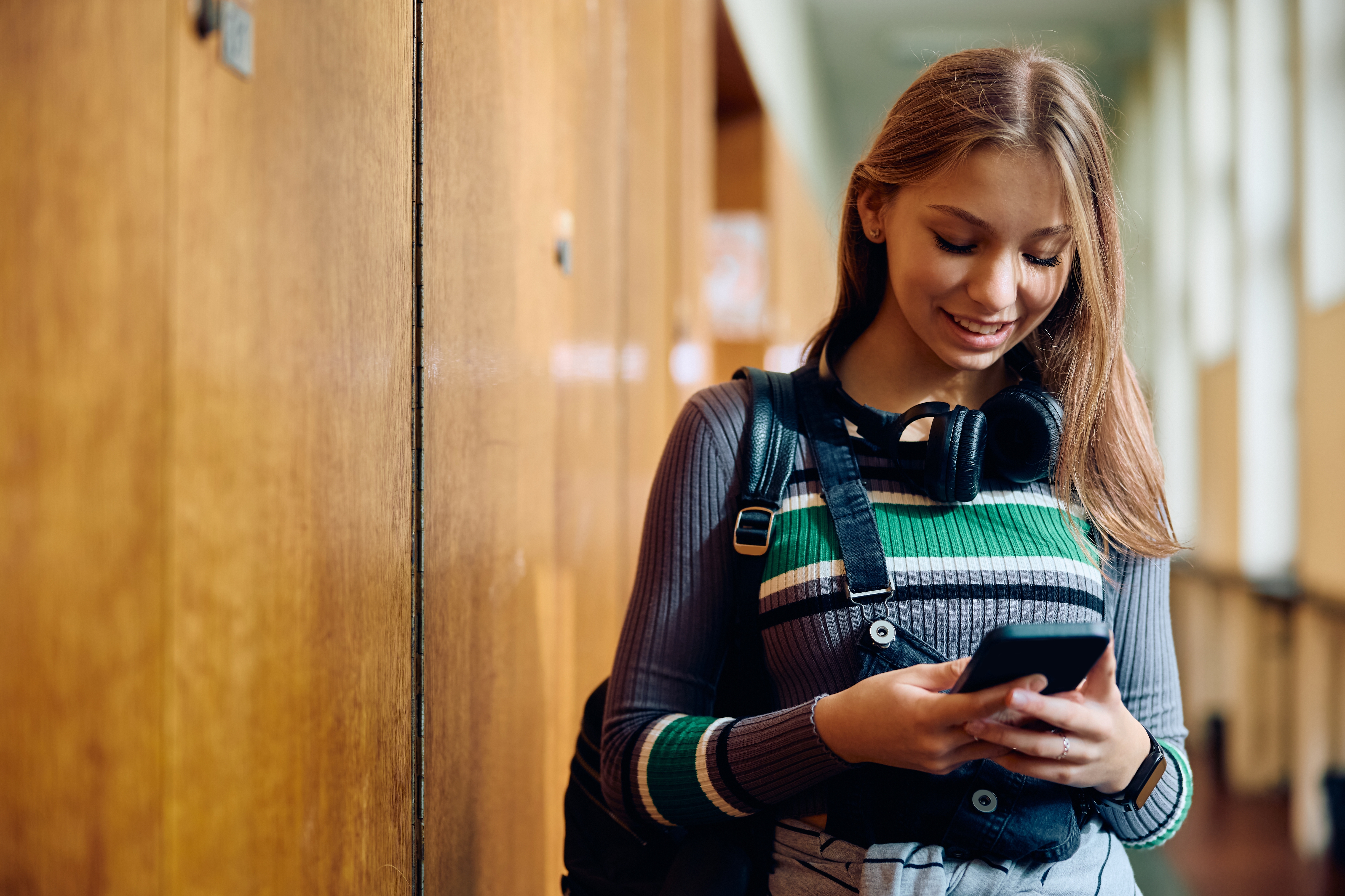 High school student smiling while using her smartphone