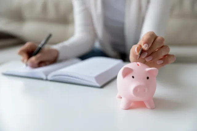 A lady dropping coins into a piggy bank