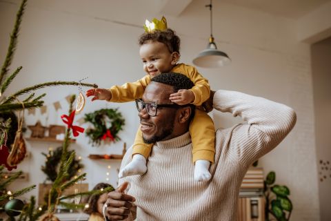 Smiling man with daughter touching Christmas ornaments at home