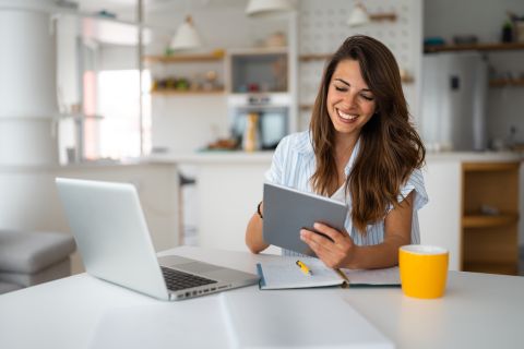 Female professional using a digital tablet while working remotely, illustrating freelancing flexibility for newcomers in Canada.