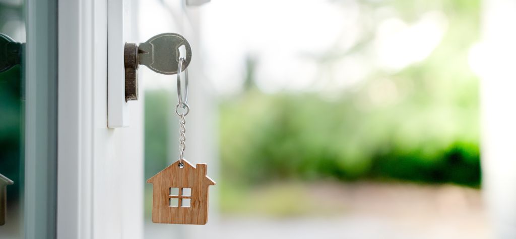 Key to the door with a wooden keyhain of a house