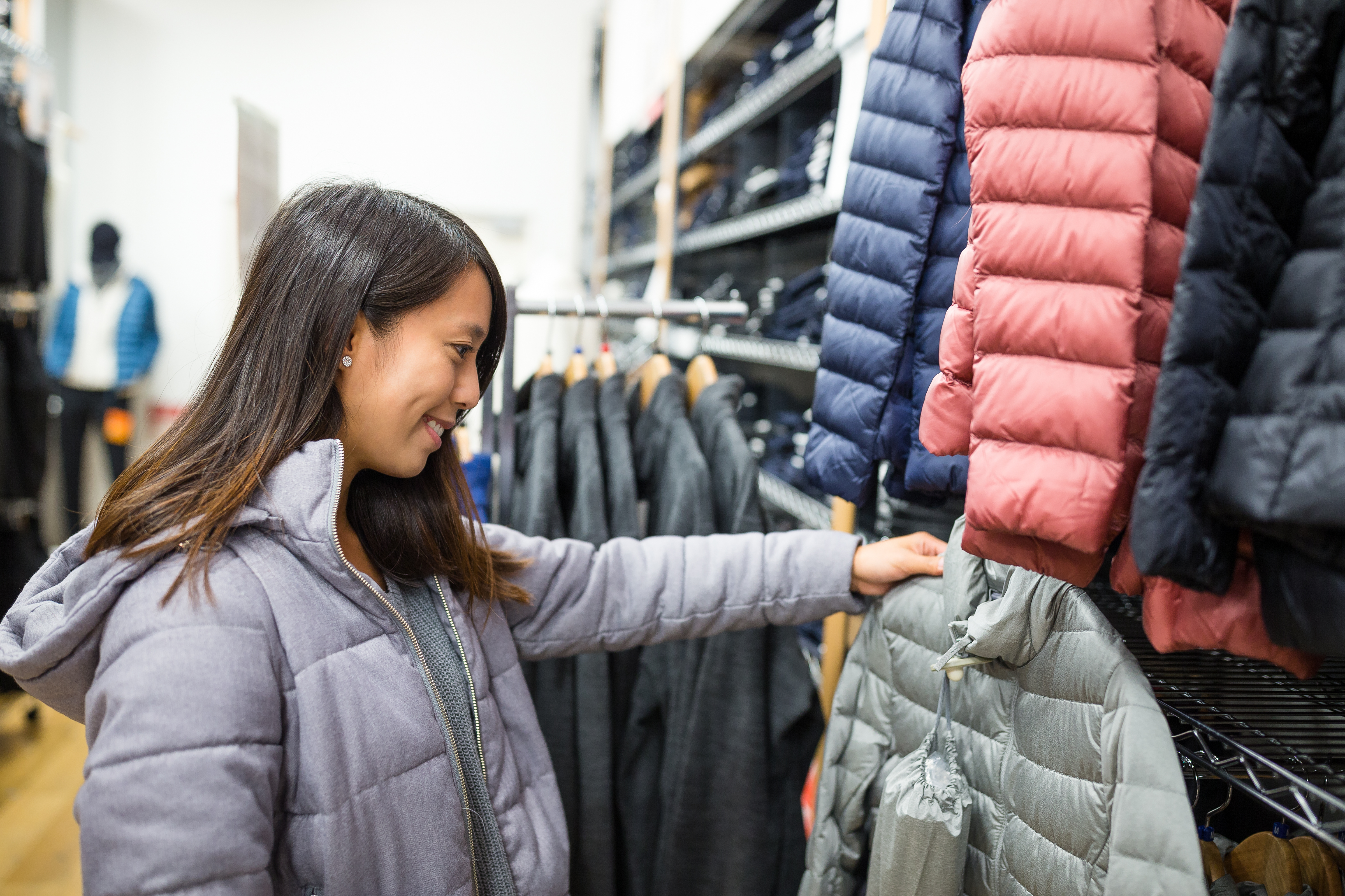 A newcomer to Canada selects a warm coat for her first Canadian winter