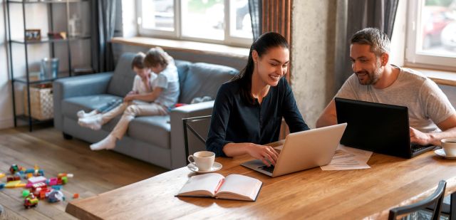 Smiling couple parents work online on laptop form home