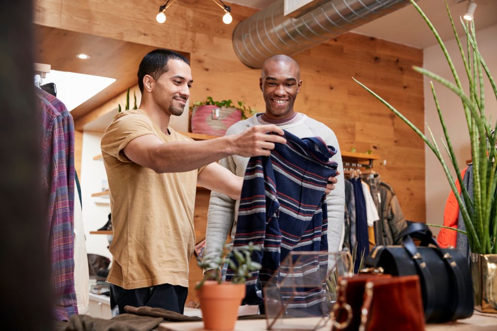 Two young men holding up clothes to look at in clothes shop