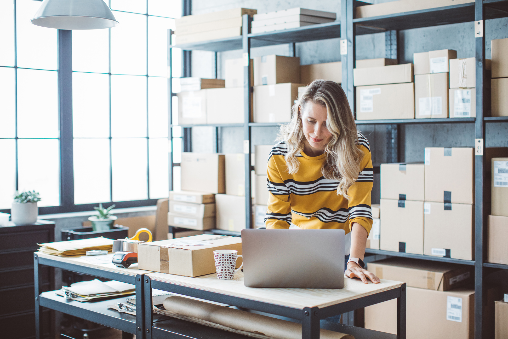 Mature woman at online shop. She is owner of small online shop. Receiving orders and packing boxes for delivery.