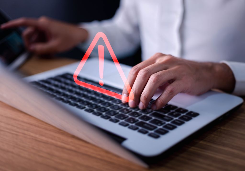 Developer using computer laptop with triangle caution warning sign for notification