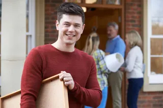 Un étudiant masculin souriant avec ses parents l'aidant à déménager