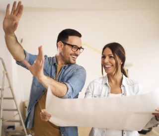 Un couple heureux qui regarde un plan directeur prévoit de rénover sa maison et d'ajouter de la valeur