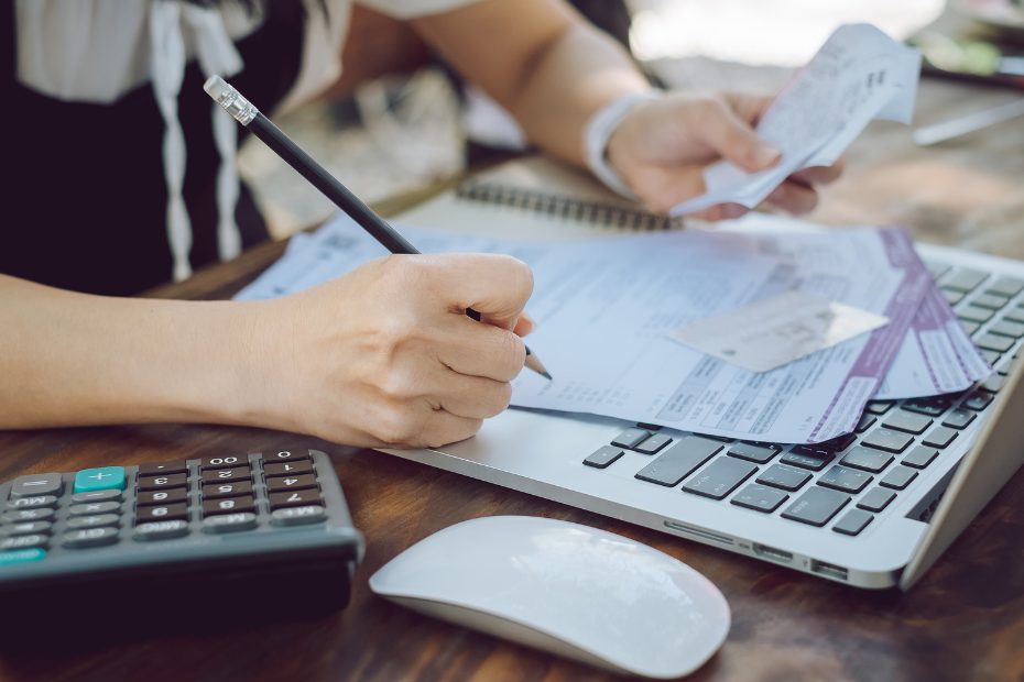 Femme à un bureau qui gère des factures à l'aide d'une calculatrice