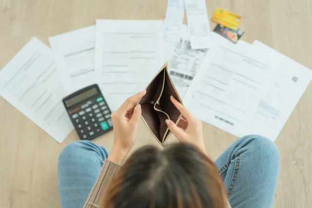 Une femme négligeant des factures et un portefeuille vide.