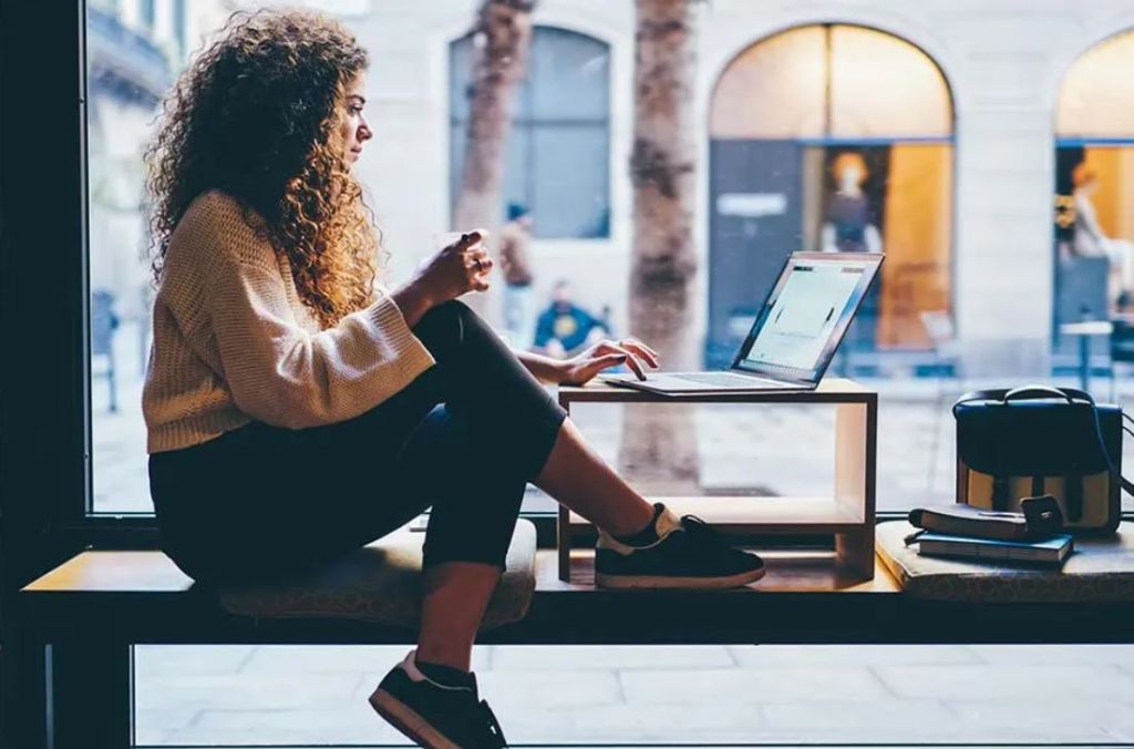 Jeune femme assise sur son bureau regardant pensivement par la fenêtre