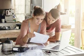 Jeune couple examinant un relevé bancaire sur le comptoir de la cuisine