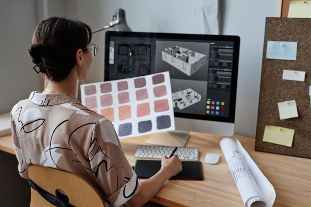 Designer féminine tenant des échantillons de couleurs tout en travaillant avec un ordinateur sur le lieu de travail