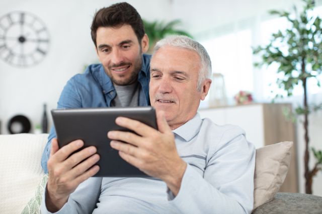 Fils et son père aîné avec une tablette à la maison