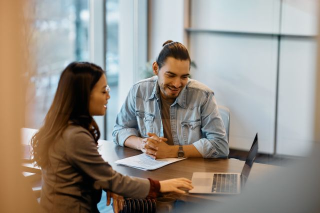 Collègues multiraciaux coopérant tout en travaillant sur un ordinateur portable au bureau