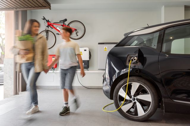 Un parent en compagnie d’un enfant recharge son véhicule électrique à une borne à domicile