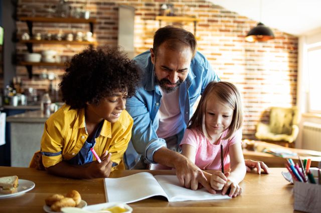 Père aidant les enfants à faire leurs devoirs à la table de la cuisine