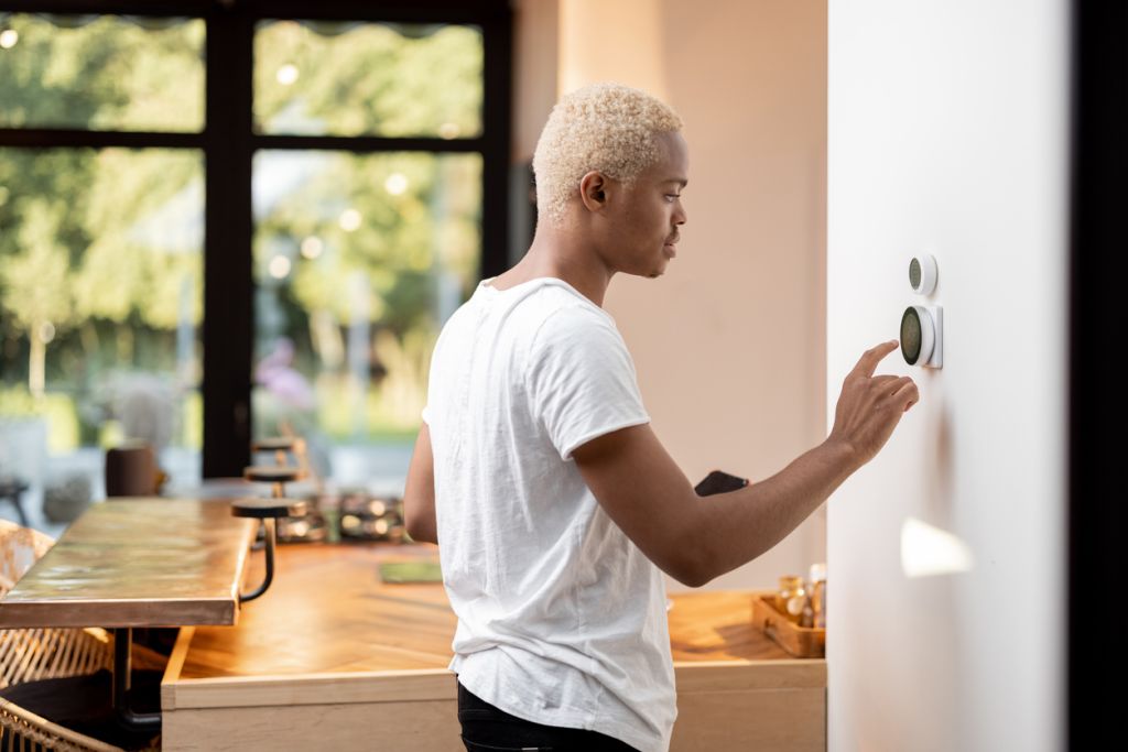 Homme latin choisissant la température sur le thermostat