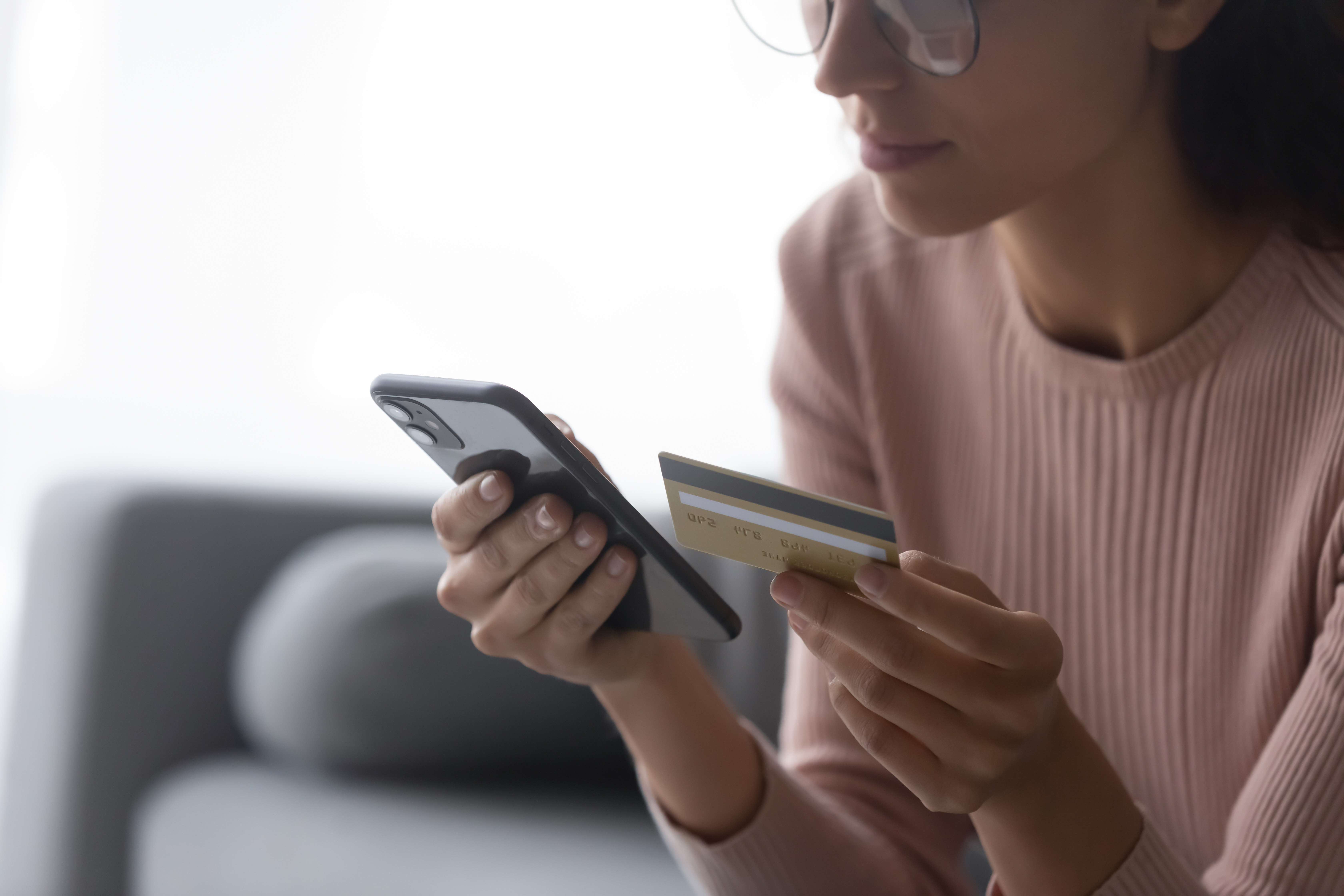 Gros plan d'une jeune femme tenant un smartphone et une carte de crédit