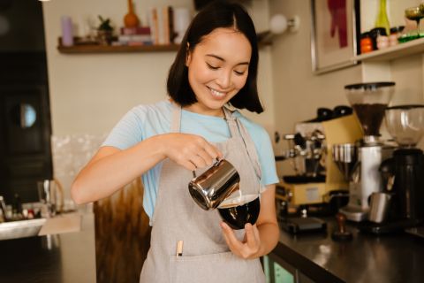 Jeune étudiant international travaillant comme barista, portant un tablier travaillant dans un café