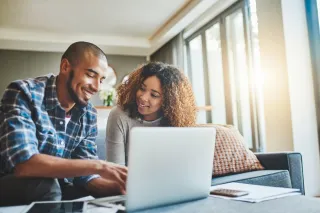 Photo d'un jeune couple utilisant un ordinateur portable tout en travaillant sur les finances de leur foyer