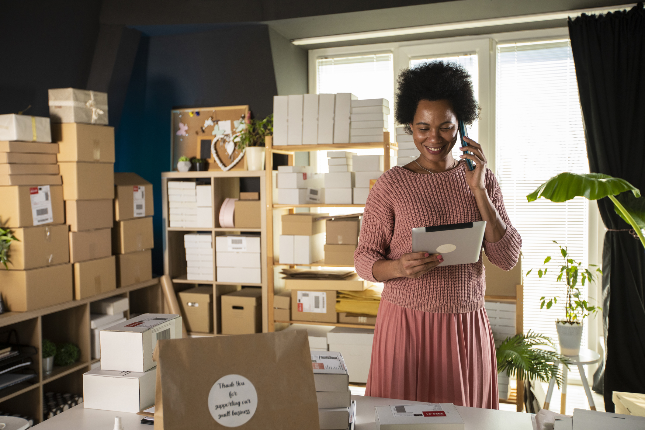 Femme propriétaire d'entreprise souriante utilisant une tablette numérique et parlant au téléphone