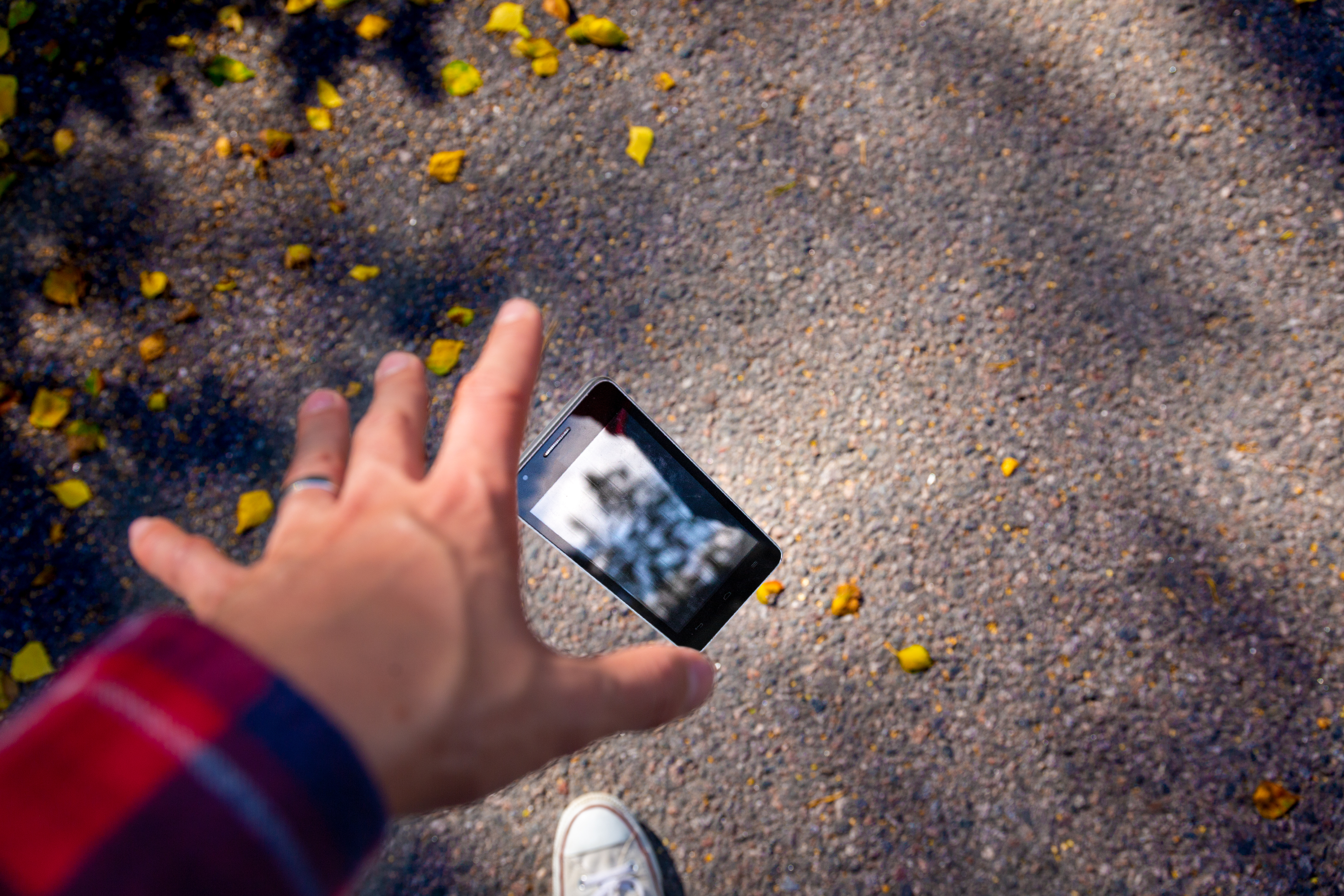 Un homme laisse tomber son smartphone et essaie de l'atteindre